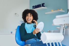 A young woman admires her teech following a dental procedure