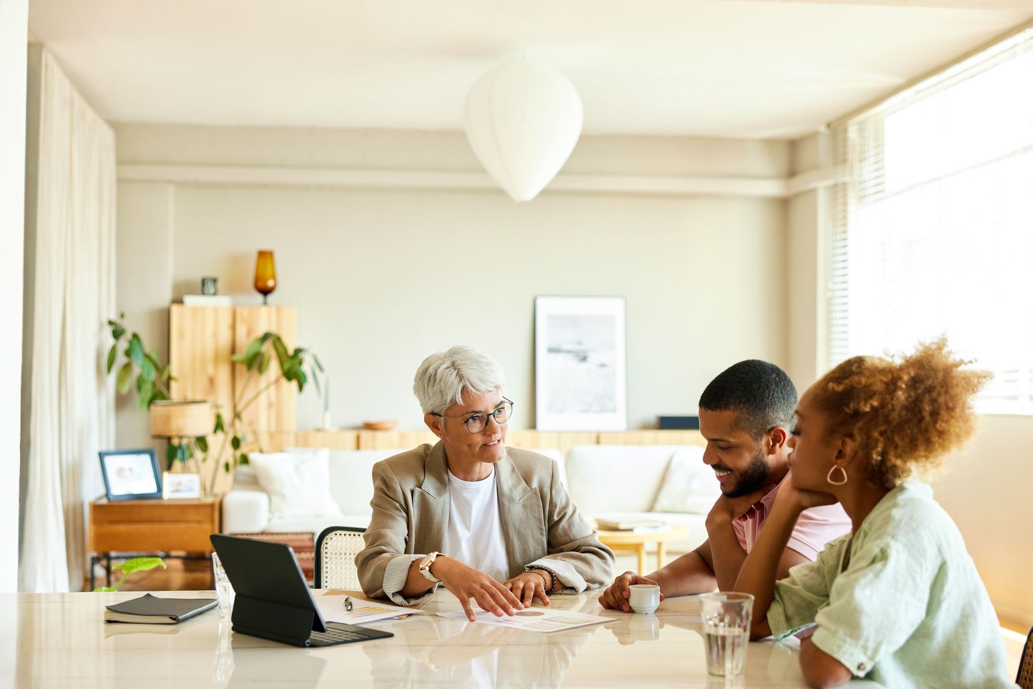 Mature female financial advisor discussing estate planning with couple in their apartment. 