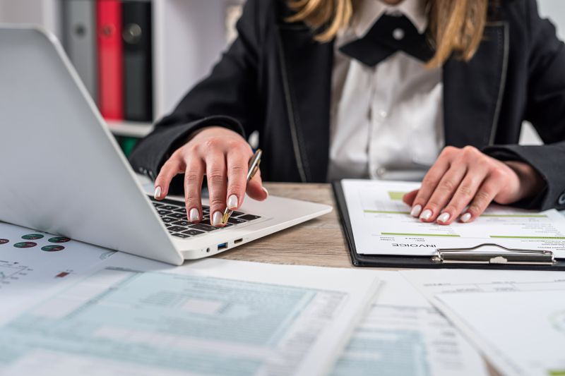 A tax accountant sits at a desk covered with IRS tax forms and schedules to file taxes for their client.