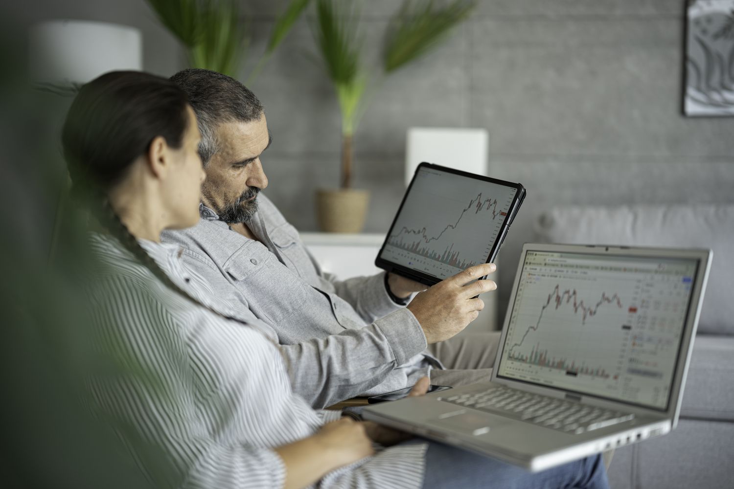 A couple sit on their couch and review the performance of their retirement portfolio after a market downturn and see one of their holding has reached a low at the zone of support. 