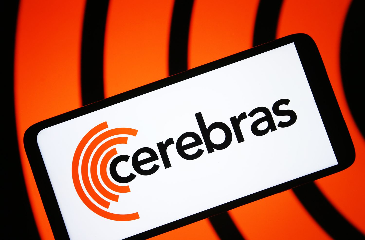 The Cerebras logo is seen on a phone screen in front of a black and orange background