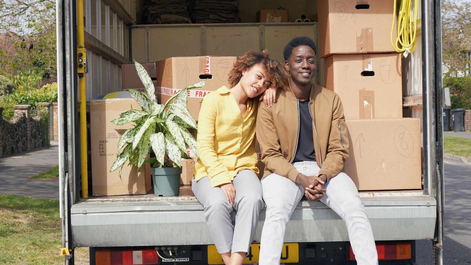 Couple Sitting on Back of Open Moving Van With Boxes