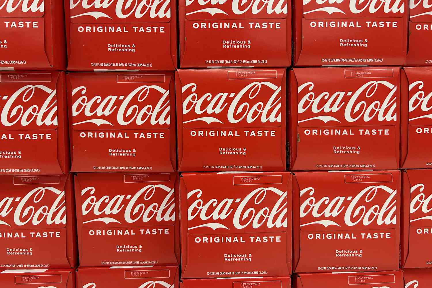 A stack of red Coca-Cola boxes sit on a shelf.