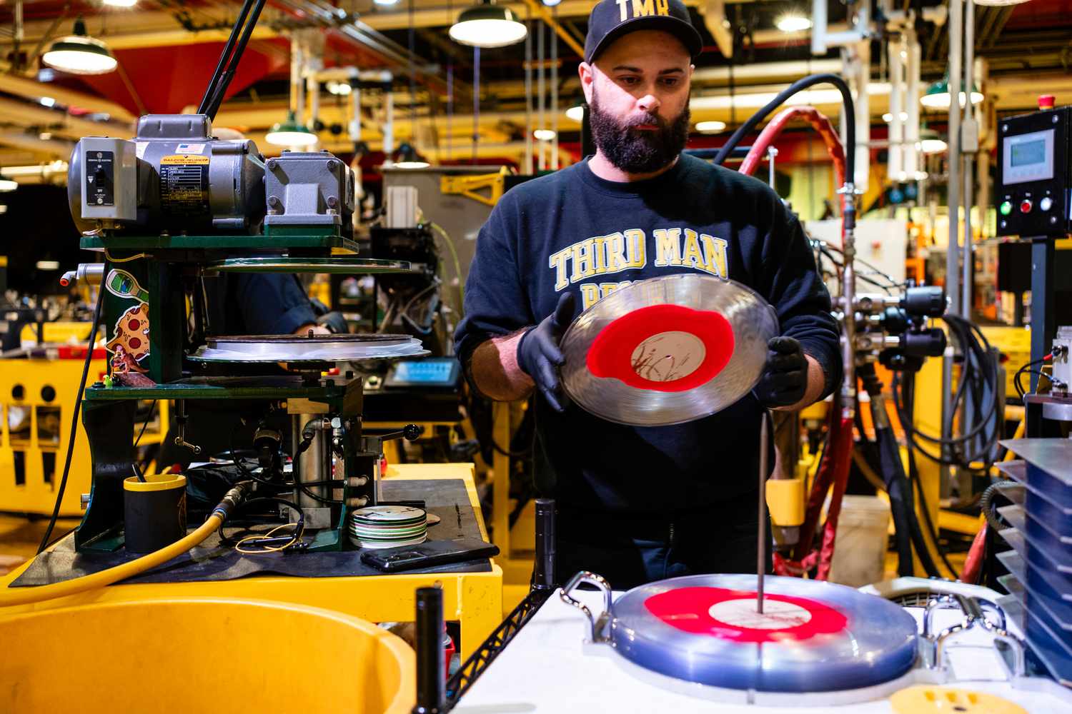 A worker removes a vinyl record from a press at the Third Man Pressing manufacturing facility in Detroit, Michigan, US, on Friday, Feb. 2, 2024.