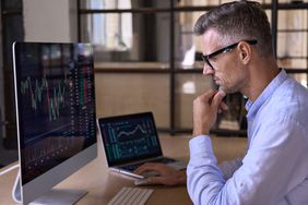 Business person sitting at computers showing financial data