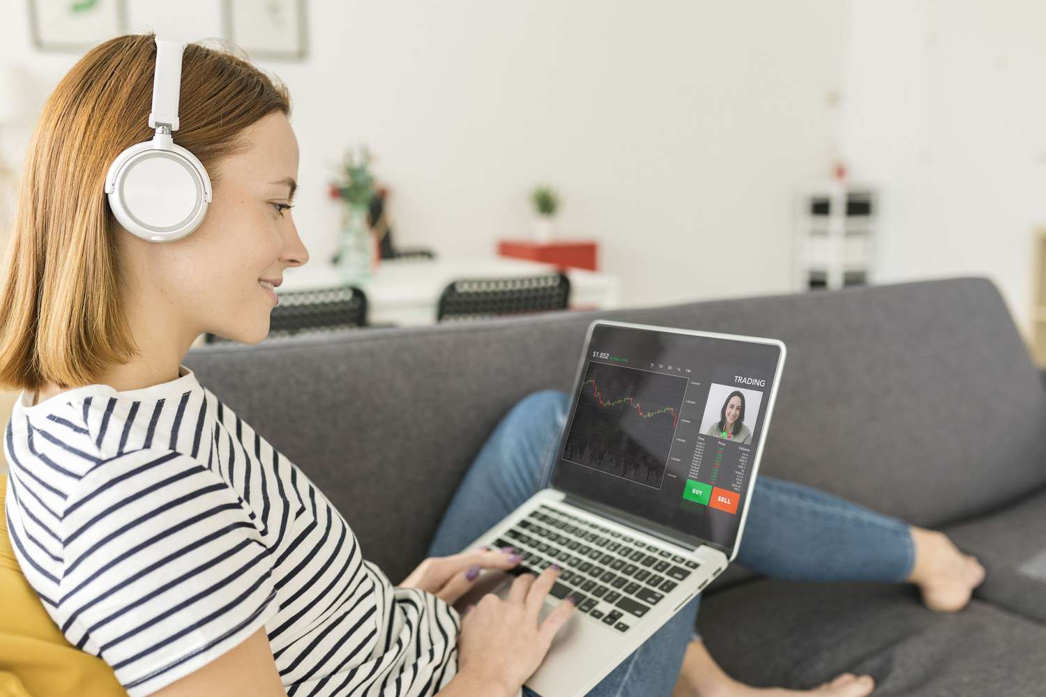Person looking at financial market information on a laptop while seated on a couch at home