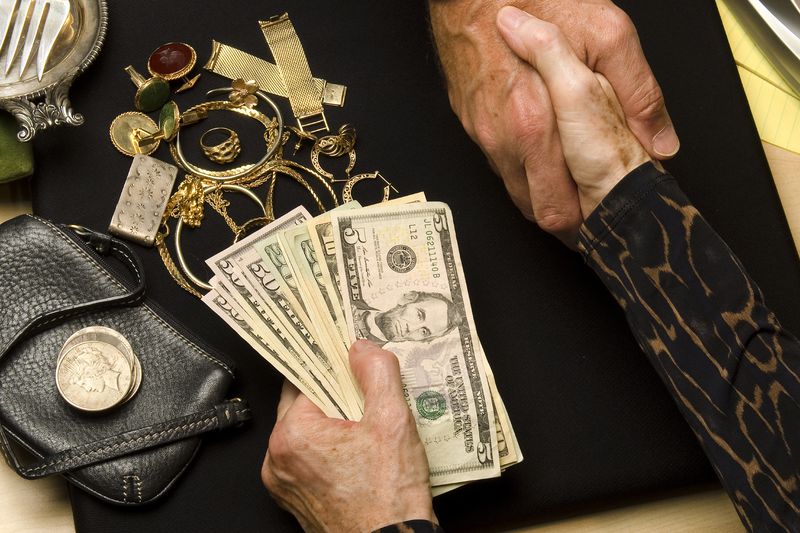 A person accepts a handful of cash as they sell old coins, jewerly, gold and silver items to a dealer.
