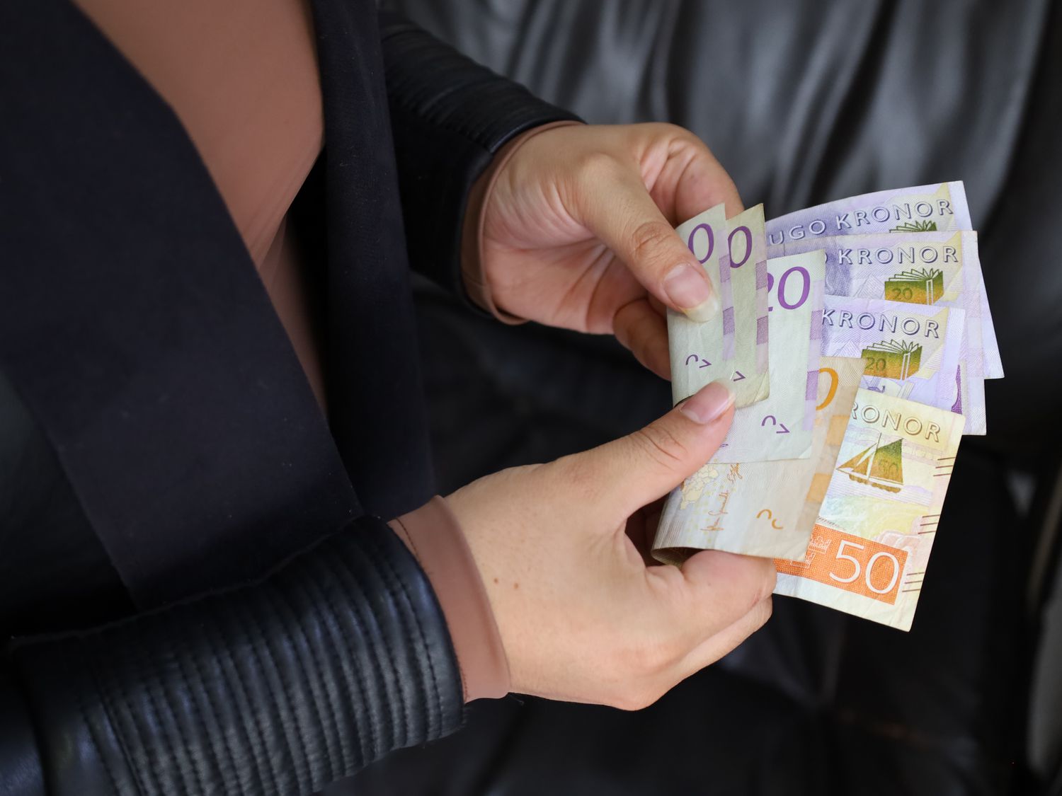 A person holding a stack of Swedish kronor banknotes