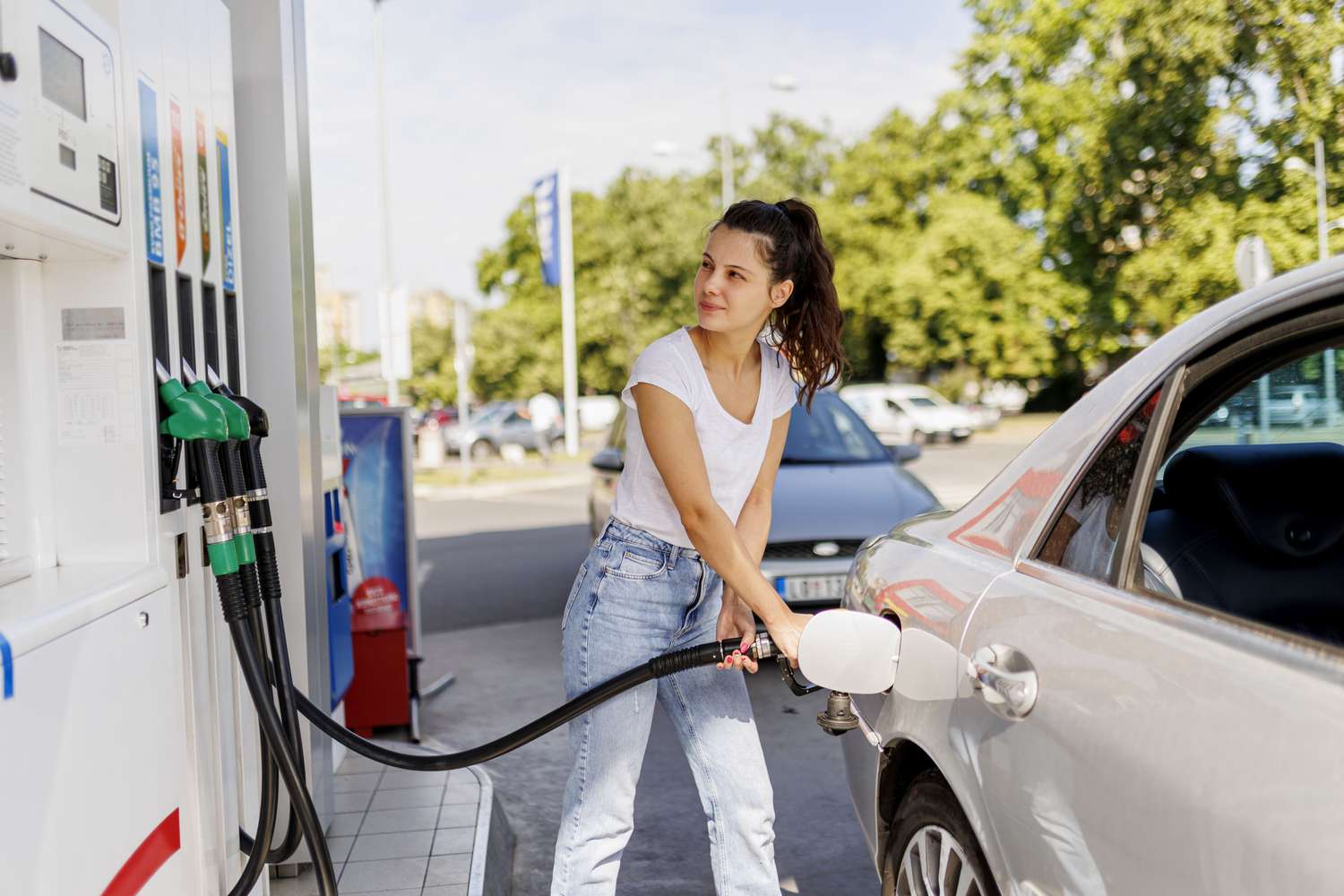 A woman fills up a car with gas at a gas station