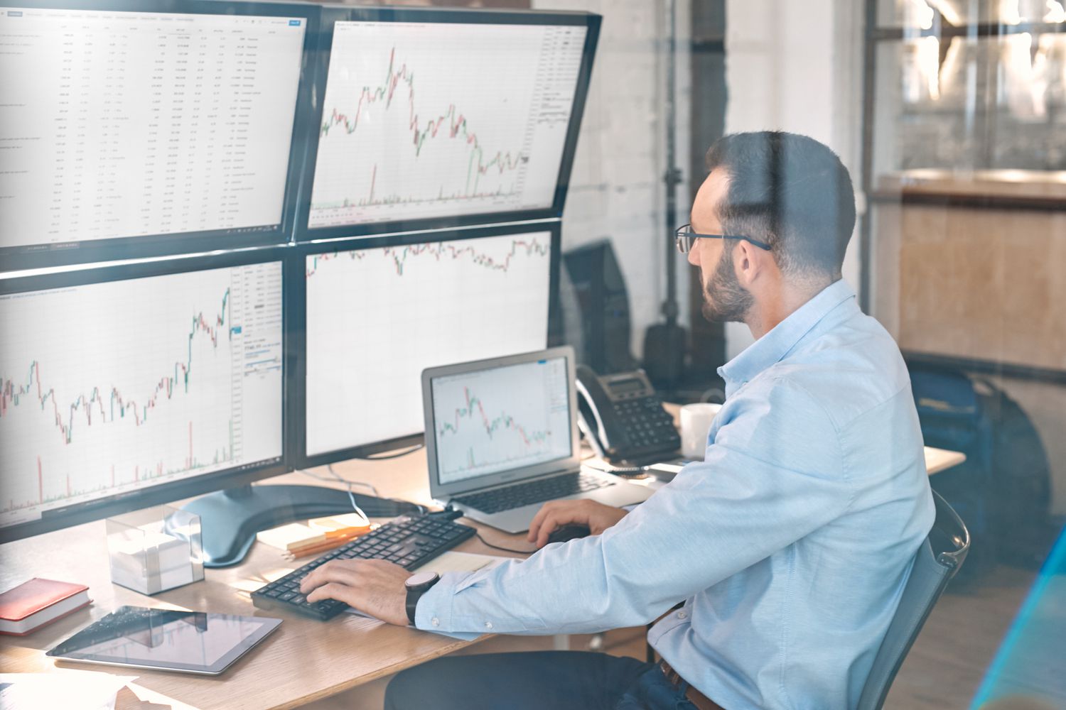Stock trader tracking different subindexes on multiple screens to make the most informed decision on trading strategies.
