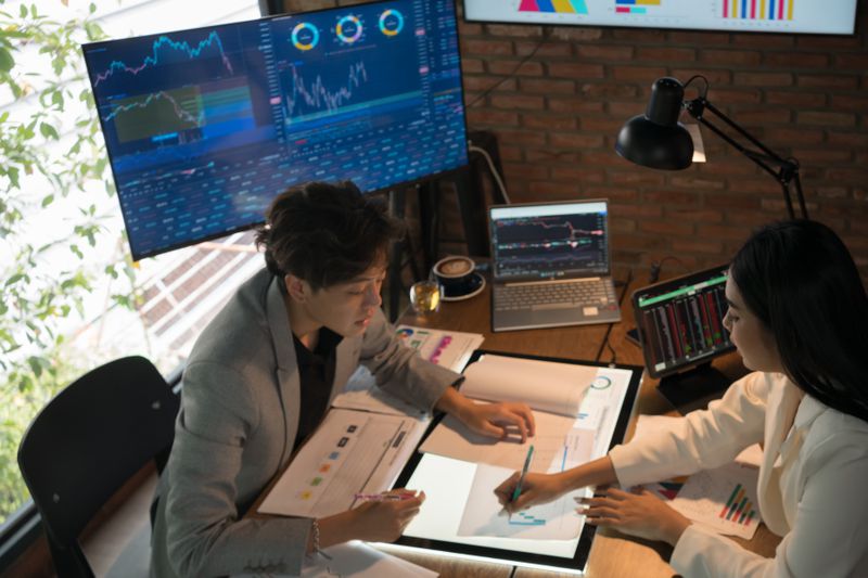 Two business people and women discussing over digital tablet at desk in office
