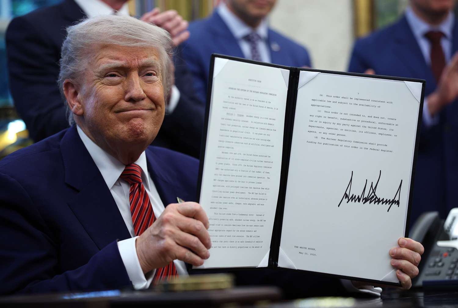 President Donald Trump holds up a signed executive order