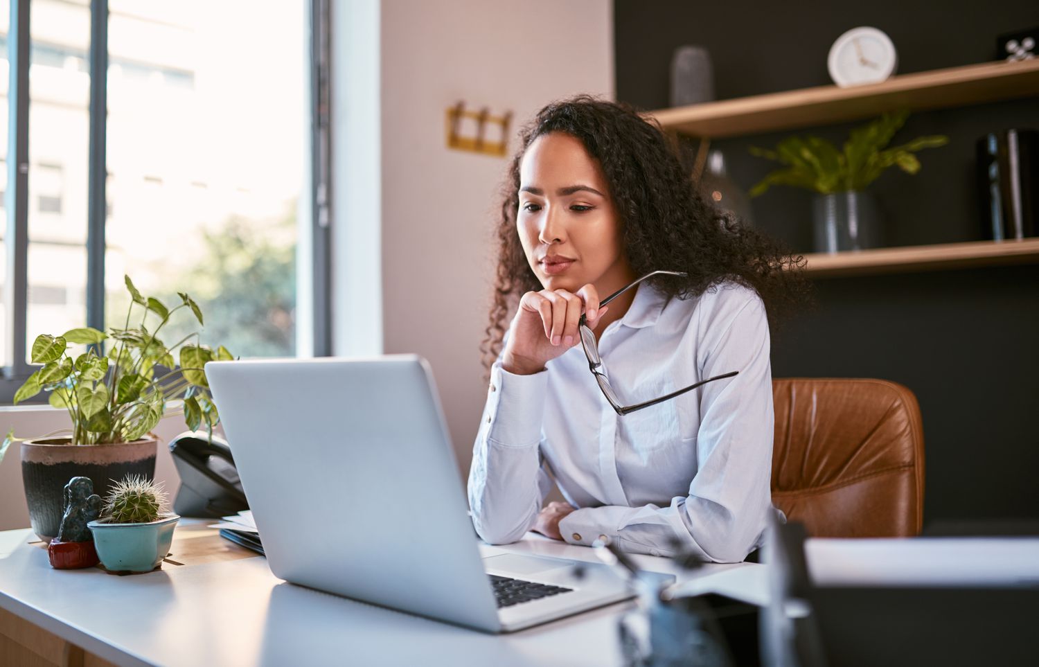 A young woman sitting at a desk and looking at a laptop