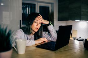 Woman looks exasperated while looking at her laptop.