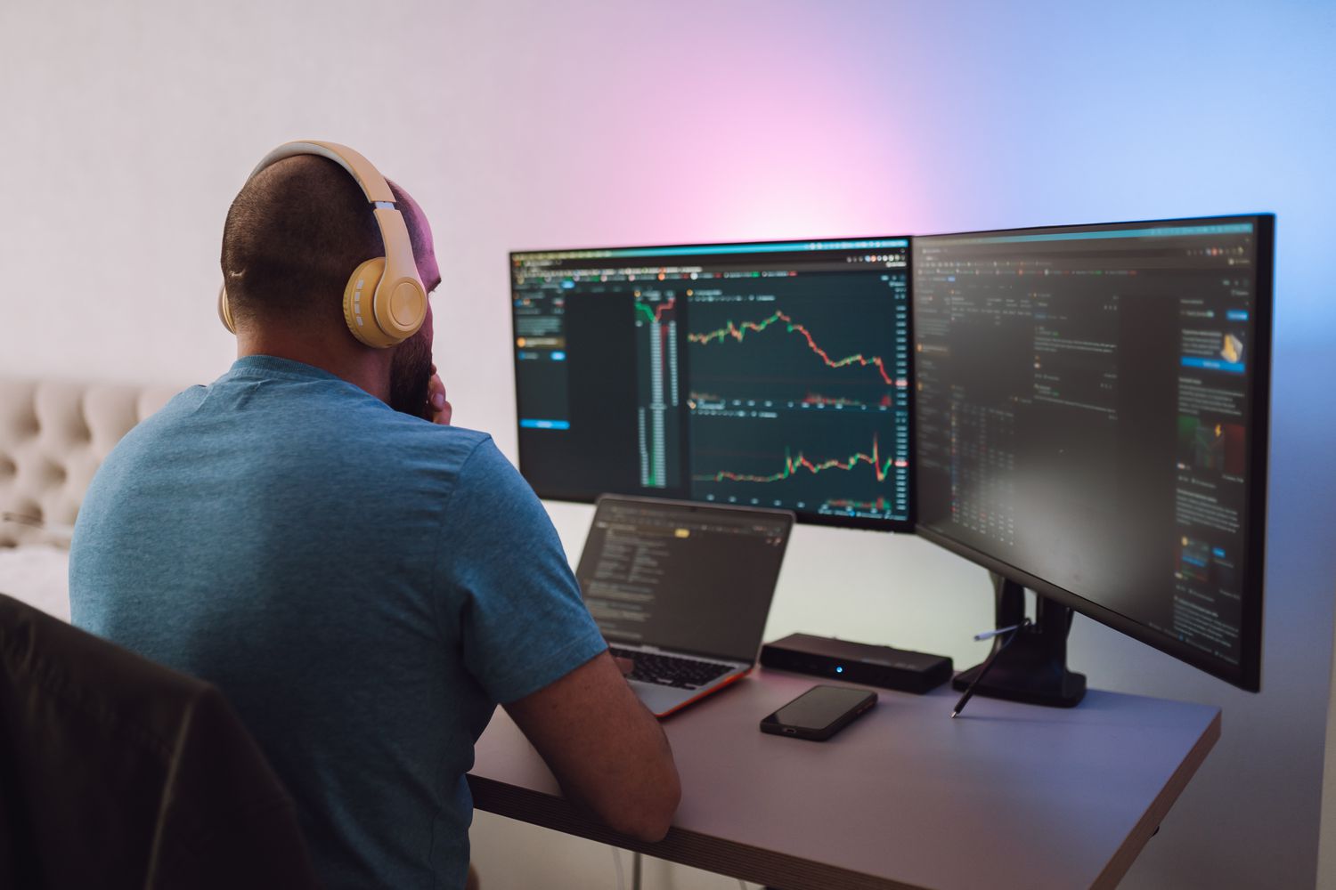 Trader sitting in home office looking at multiple trading screens