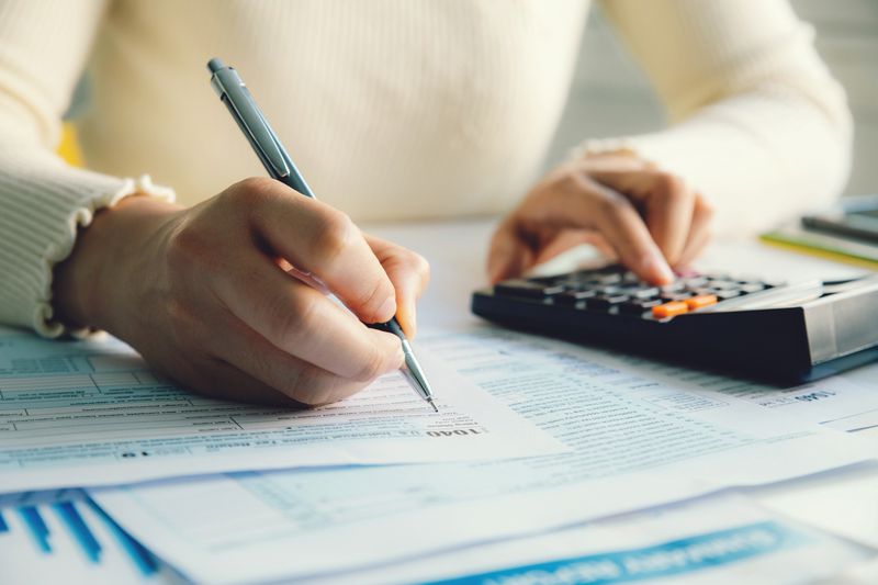 Cropped body section of woman doing taxes with pen and calculator