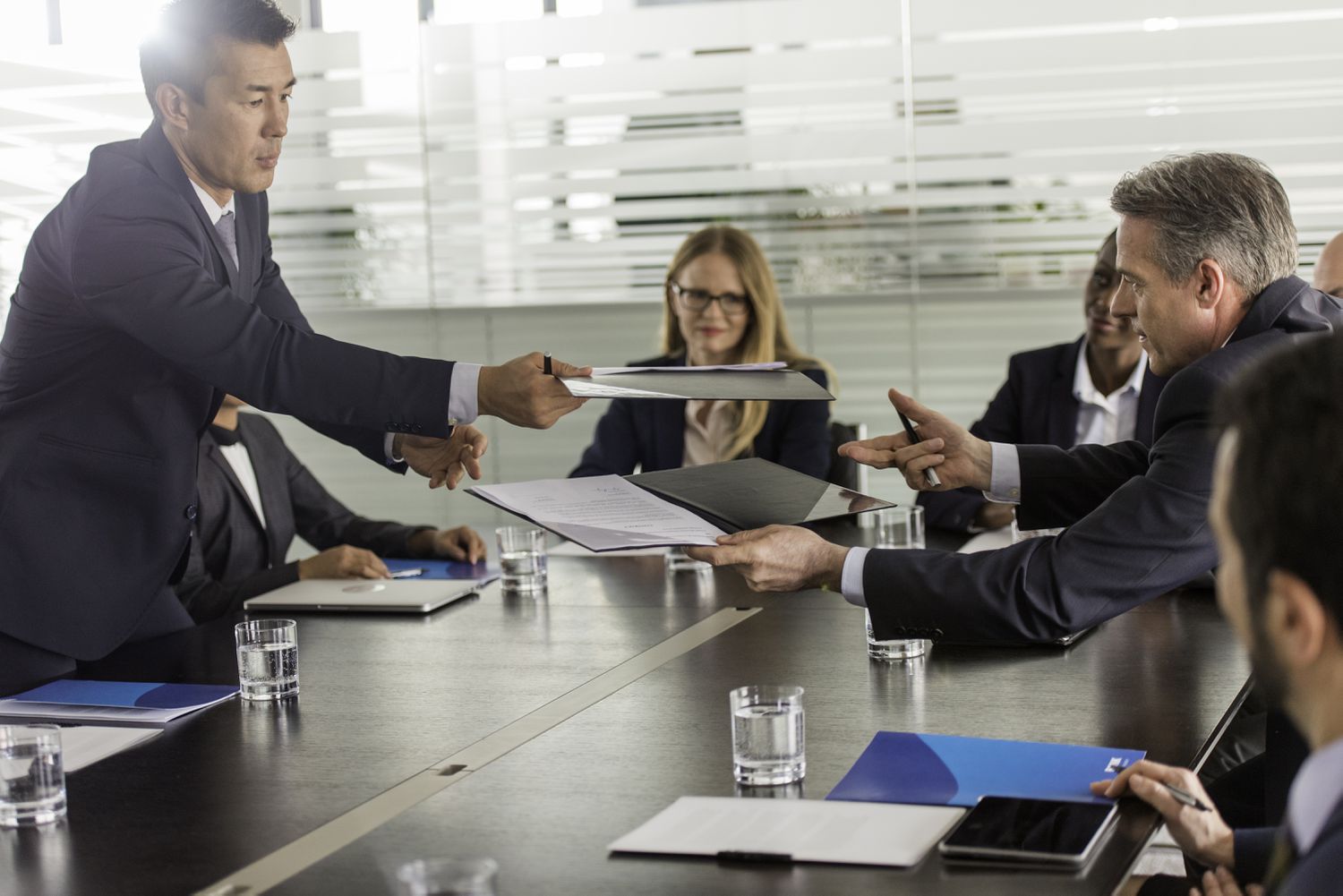 Mortgage lender and third-party mortgage originator exchanging documents and signatures to finalize their partnership.