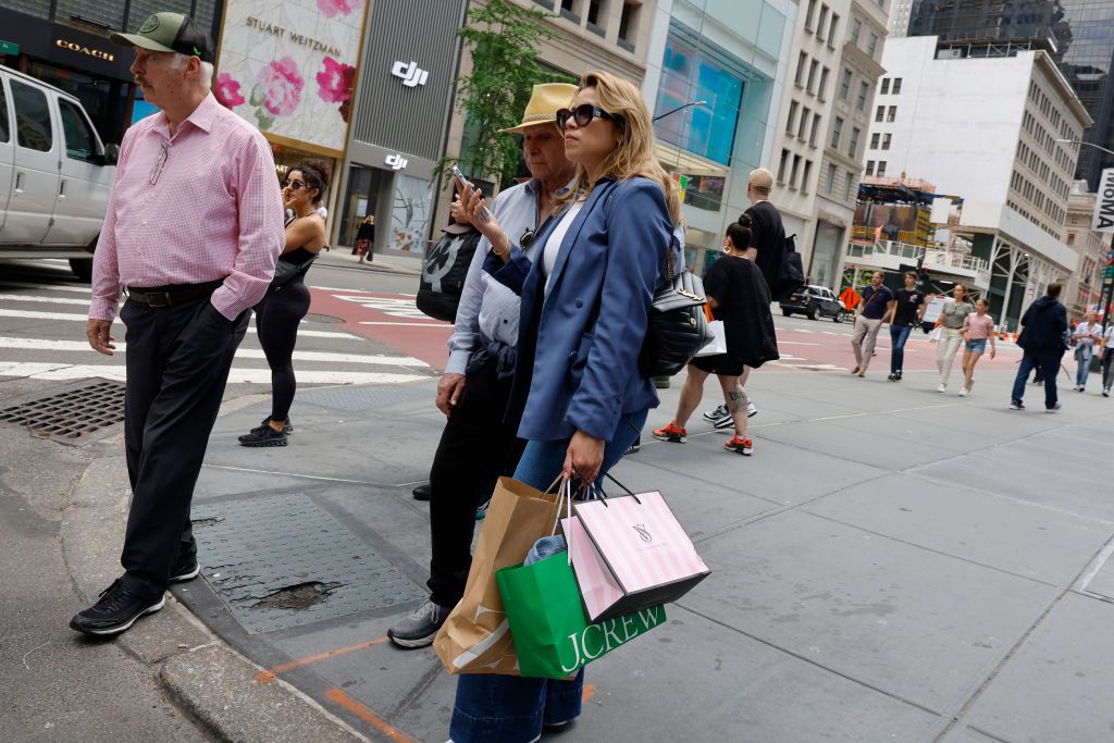 People walk along Fifth Avenue with shopping bags on May 08, 2024 in New York City.