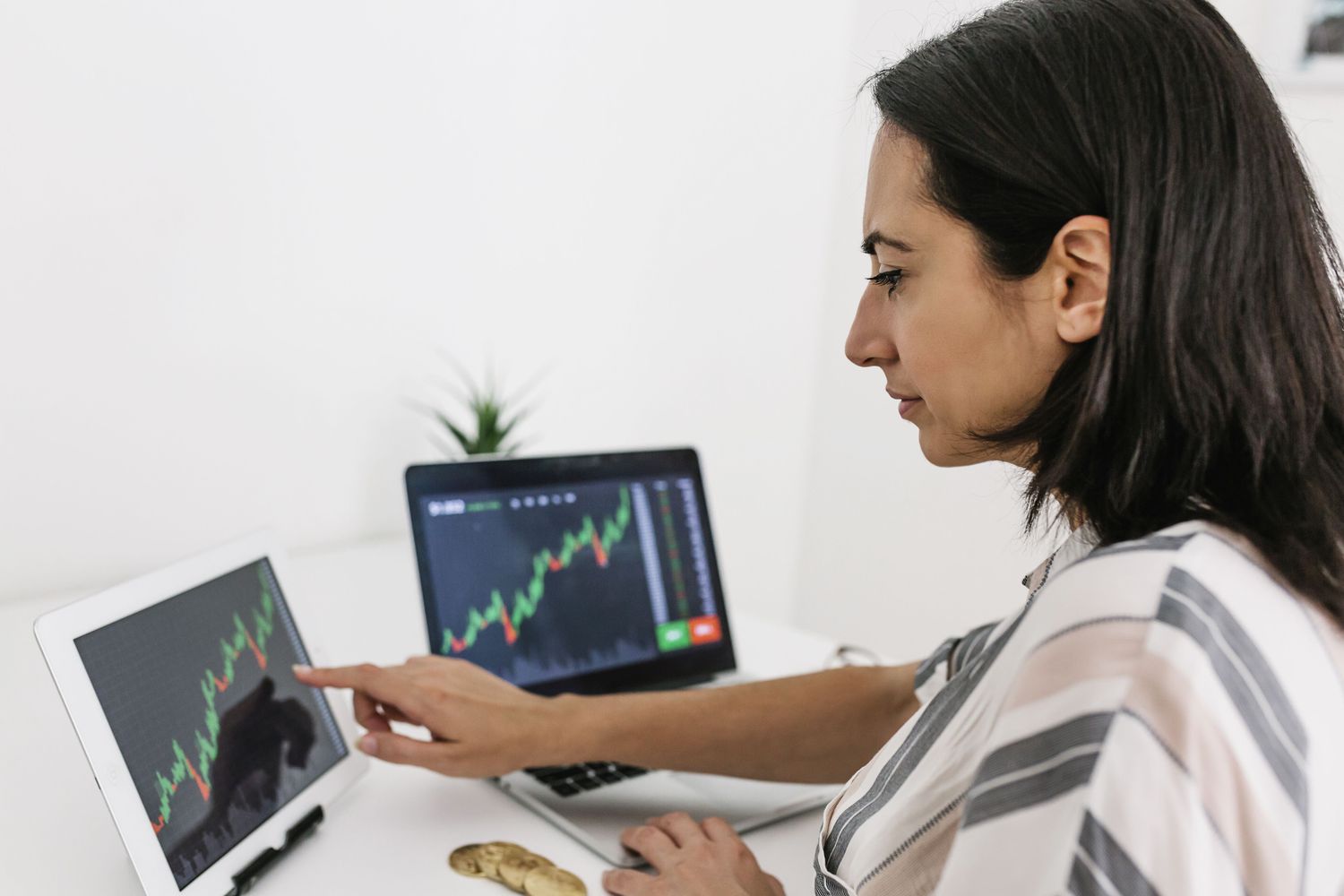Woman checking market data on two computer screens