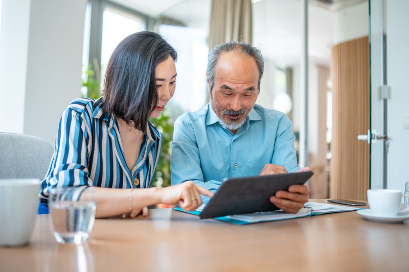 Older couple sitting at their dining room table and looking together at mortgage rates on a tablet