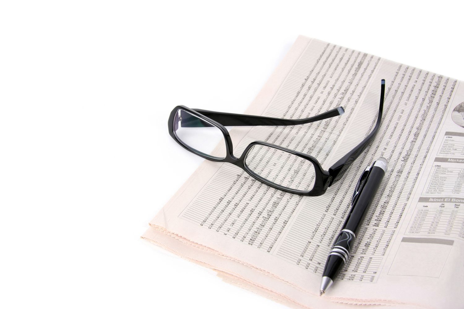 Financial newspaper with a pen and eyeglasses.