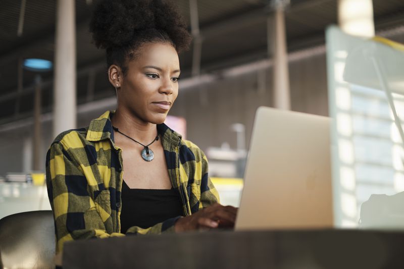 Woman sits on computer at a desk reading the Kraken review from Investopedia