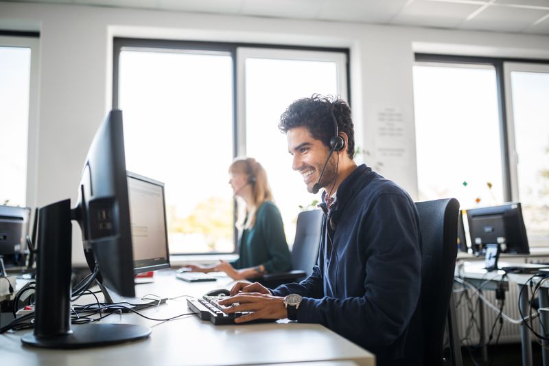 Smiling customer service representative using computer at desk