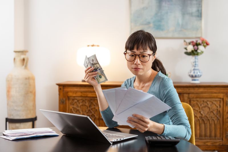 A person holding envelopes in one hand and cash in other hand. 