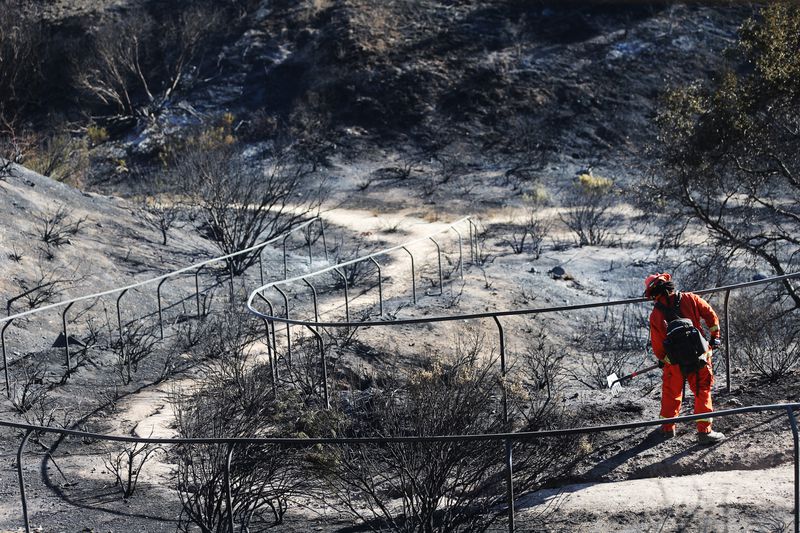 An inmate firefighter works to put out hot spots in a California wildfire.
