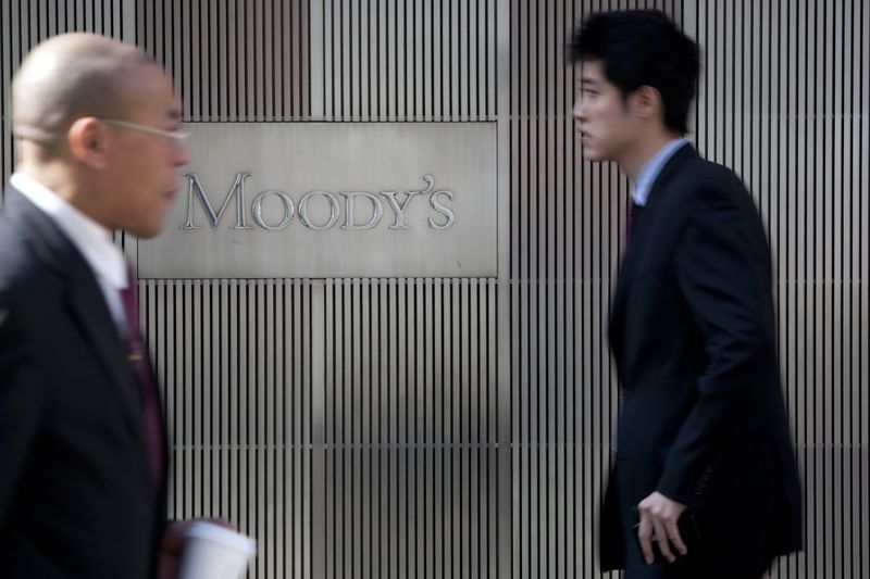 People walk outsided a building with the Moody's sign.