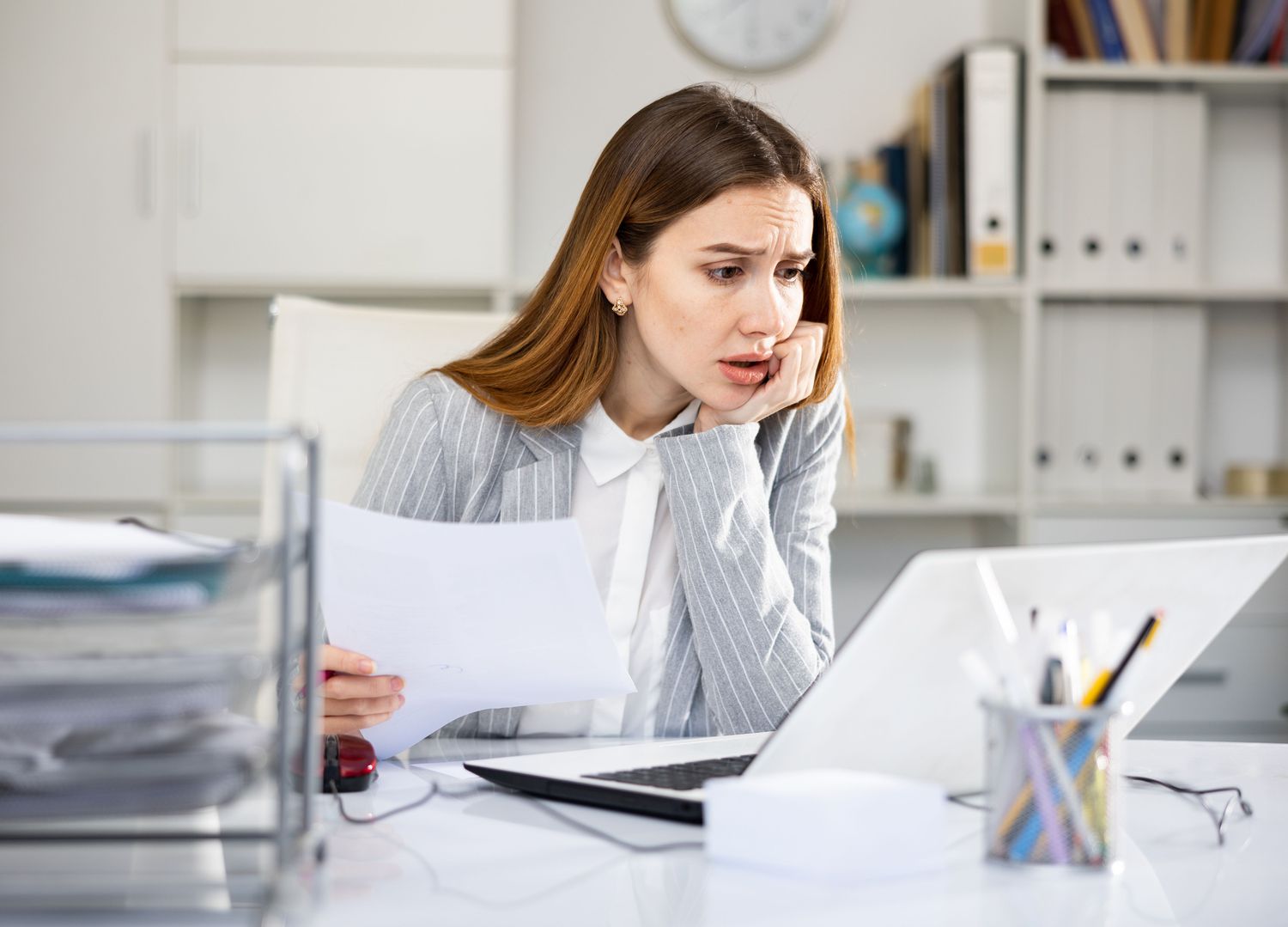 Woman looking with concern at a laptop screen in an office