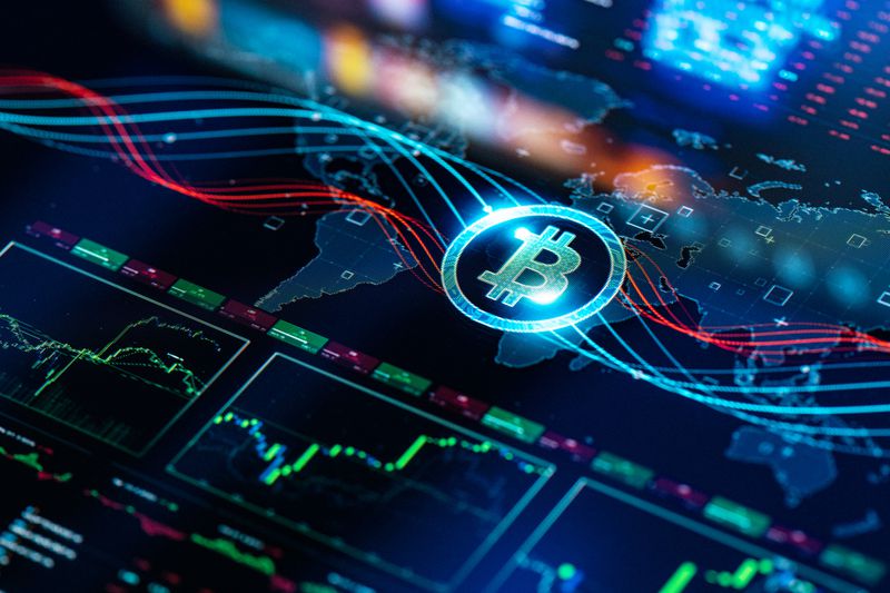 Bitcoin logo on top of screen with trading charts and images of continents