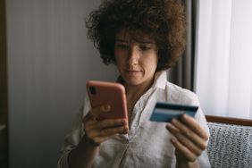 Young adult looking up information about whether or not applying for a new credit card can hurt credit score on the phone.
