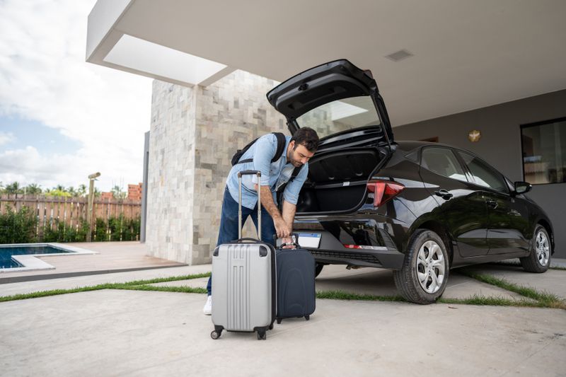 A man loads luggage into the trunk of a rental car