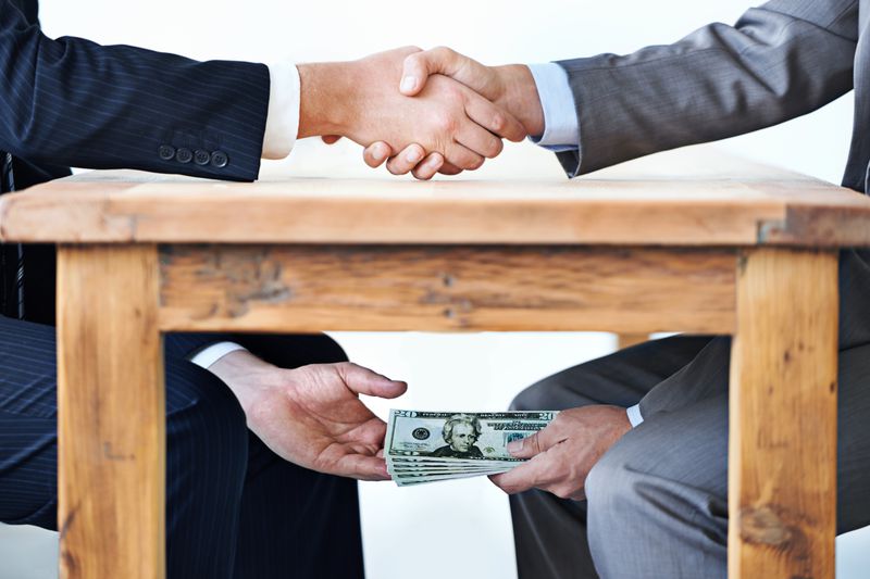Corrupt businessmen exchange money under the table.