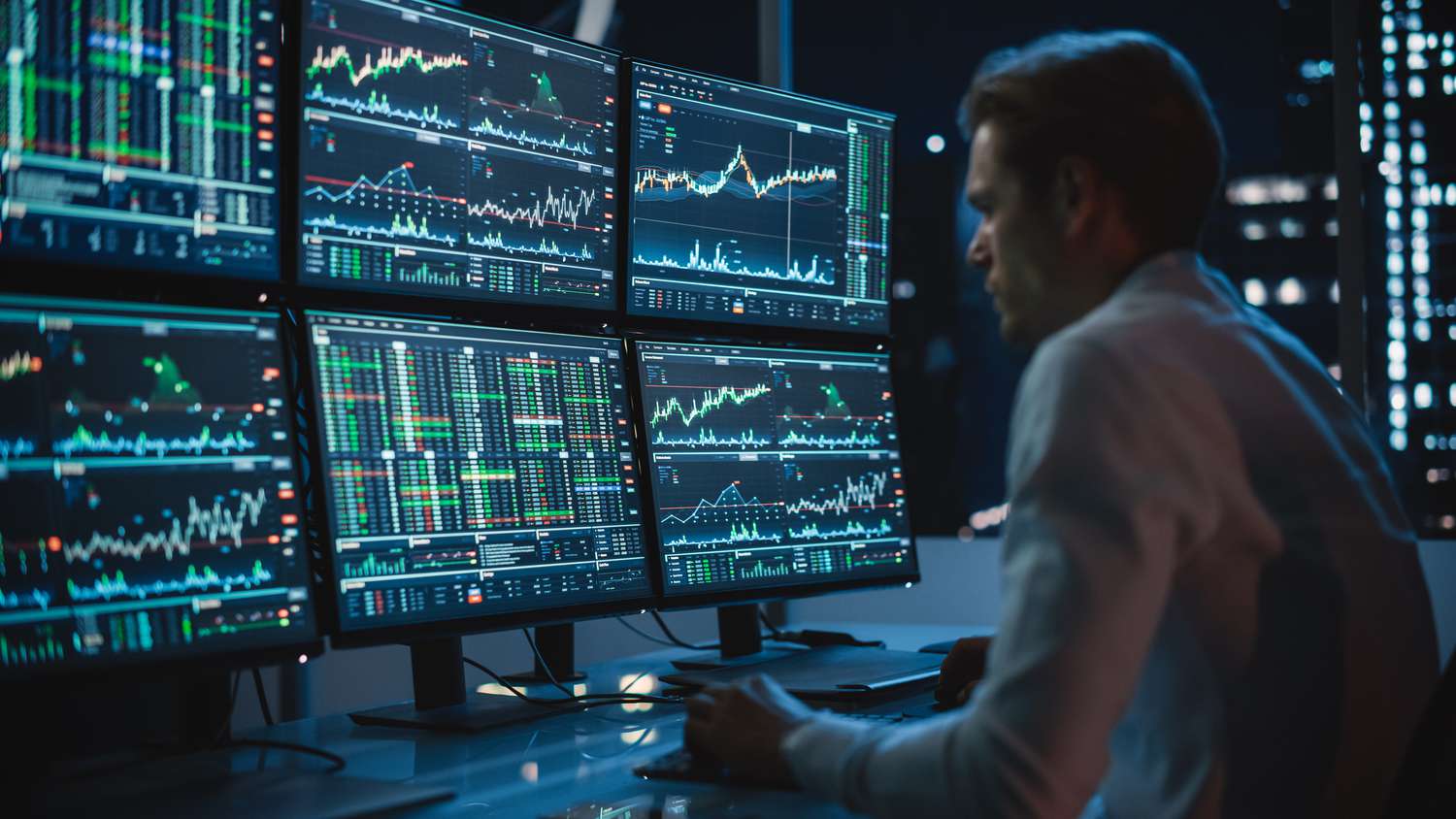 A market maker in front of multiple monitors with market charts