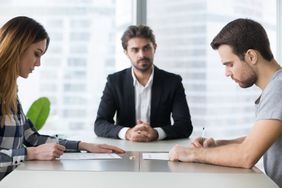 Man and woman signing divorce decree papers in lawyer’s office