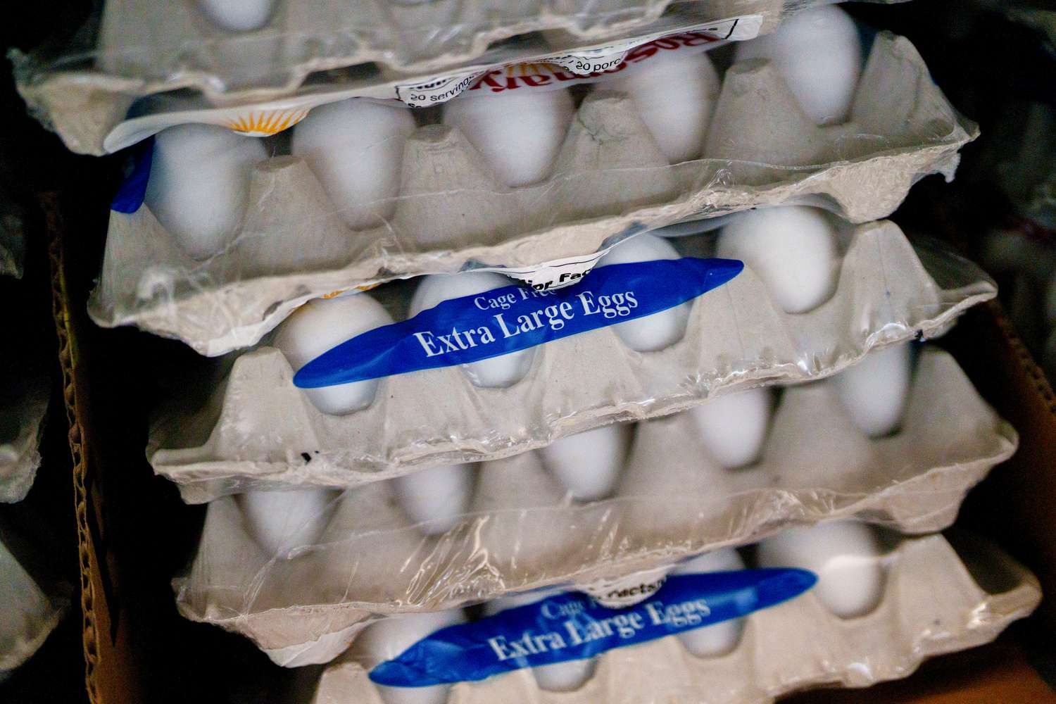 A stack of egg cartons are seen with a blue label that says Extra Large Eggs.