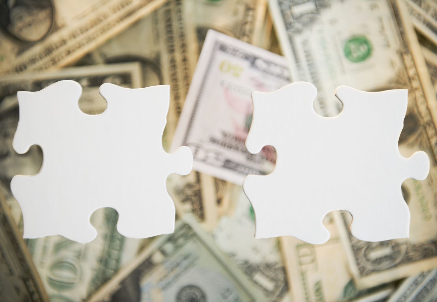 Puzzle pieces over a pile of money