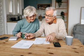Older couple looking at paperwork at kitchen table