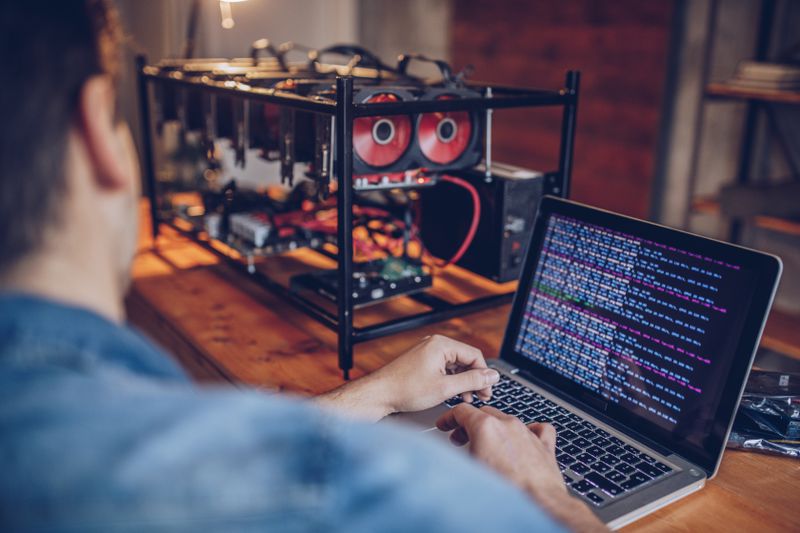 A person sitting in an office using a computer and mining cryptocurrency