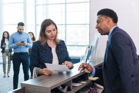 A male bank manager talks to a woman at the bank counter.