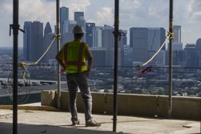 A worker standing in a building under construction and looking out at the view.
