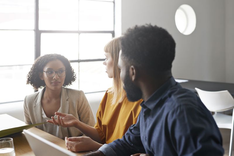 Three coworkers talking in a meeting in an office