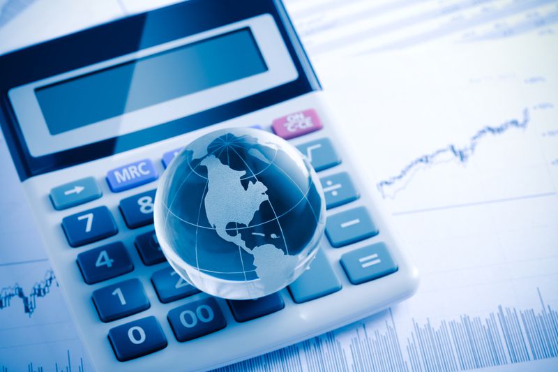 A calculator and crystal globe (america map) on a stock charts.