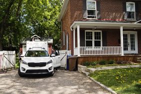 white car parked outside of a two story house with people in the car and others getting in