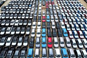 Dozens of vehicles in a range of colors are sitting on a dock, prepared to be exported from China.