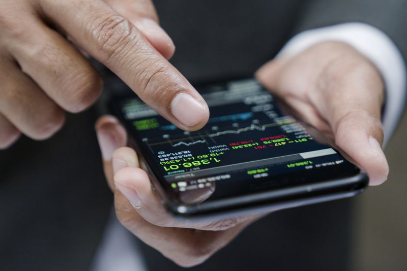 A man uses a phone to look at trading data