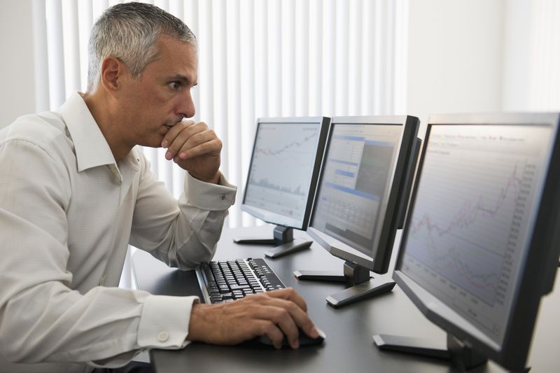 A broker working on three computers.