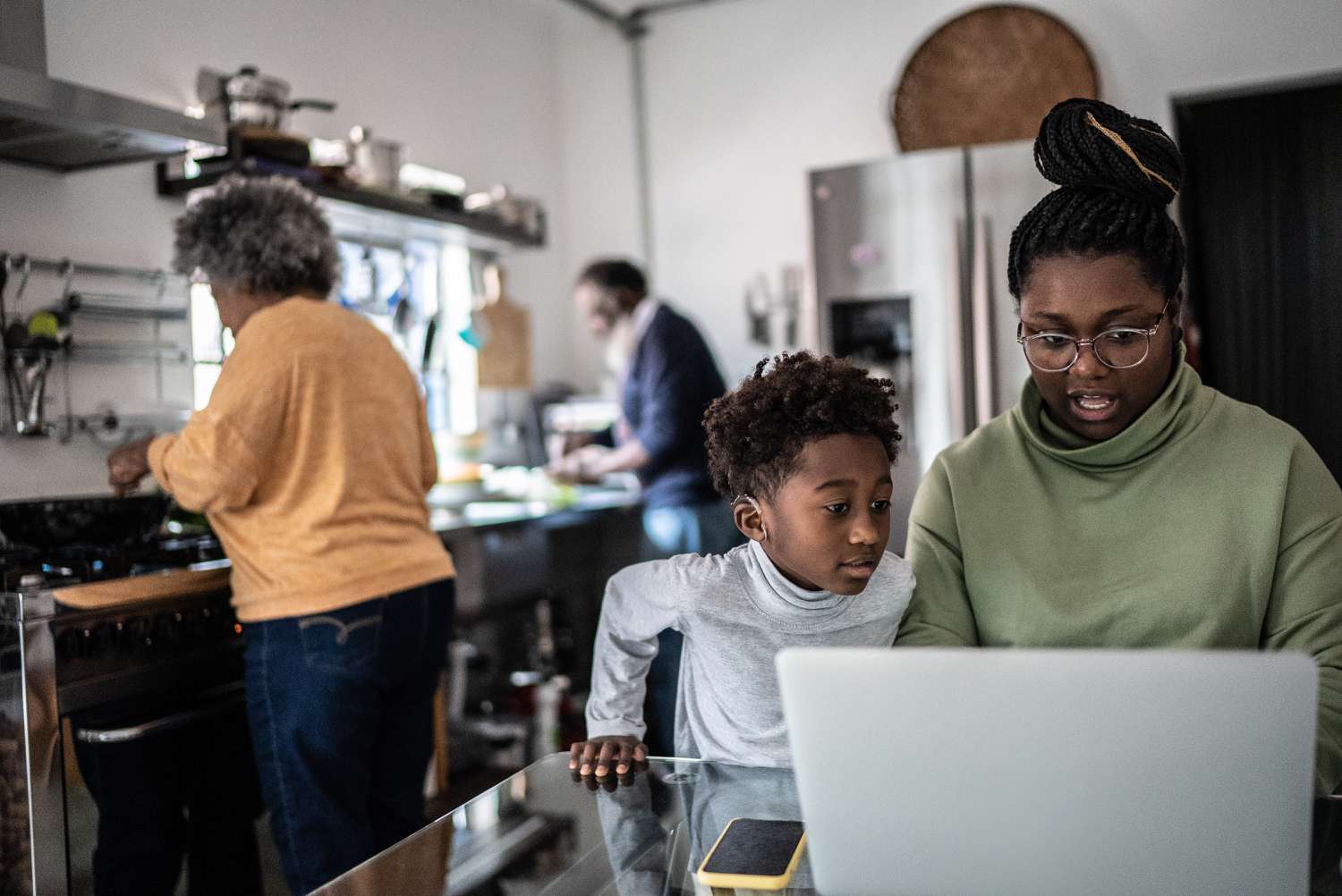 Mother and son using laptop in the kitchen at home